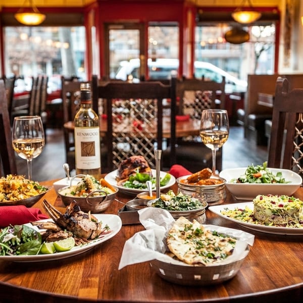 A restaurant table set with a feast of diverse dishes, white wine, and glasses.